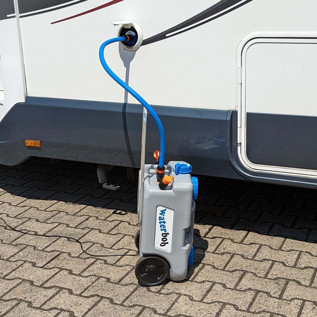 Der WaterBob steht am Wohnmobil, der blaue Schlauch führt in den Einfüllstutzen